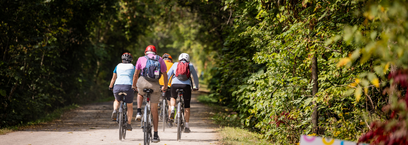 Cyclists riding on a paved trail through the woods