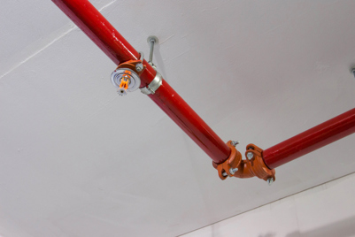 Sprinkler Systems A red piped sprinkler system hanging from the ceiling of a building